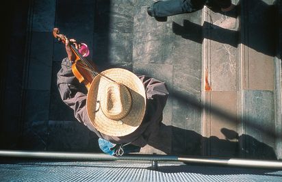 Vogelperspektivische Ansicht einer Person auf Treppenstufen mit Hut, die Violine spielt.