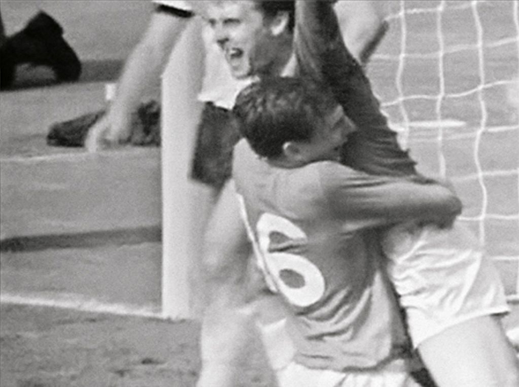 Black and white photograph of two soccer players hugging each other in cheers