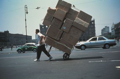 Eine Person zieht eine sehr große Menge Kartons auf einem Sackkarren die Straße entlang.