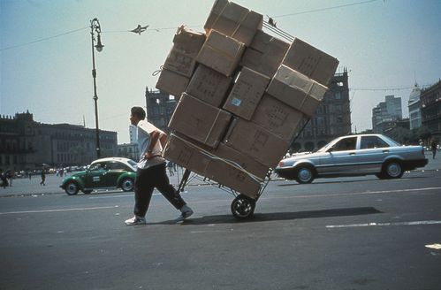 Eine Person zieht eine sehr große Menge Kartons auf einem Sackkarren die Straße entlang.