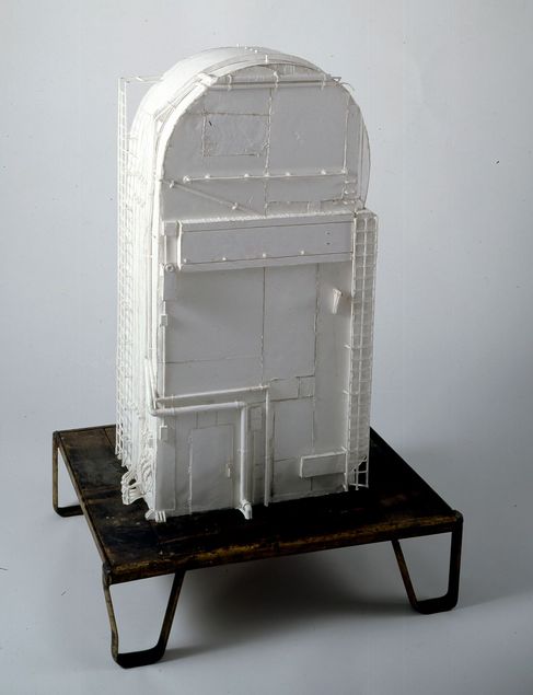 Auf einem tiefen Sockel steht ein vollständig weißes Modell eines sogenannten Service Masts (engl. Tail Service Mast), wie er bei Raketenstarts verwendet wird. Über das U-förmige Gebäude verlaufen Rohre und Kabel. Unten links ist eine kleine Tür sichtbar, an der rechten Seite des aus Schaumplatten angefertigten Korpus ist eine schmale Leiter angebracht.