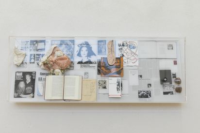 Plexiglasschaukasten, in dem collagenartig verschiedene Schriftstücke und Objekte ausgestellt sind: Unter anderem mediale Ausschnitte zu Brigitte Bardot, literarische Werke die sich mit weiblichen Rollen(bildern) beschäftigen und weiblich konnotierte Accessoires.