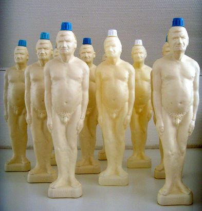 Several identical white plastic bottles shaped like a naked man, with blue screw caps at the top. 