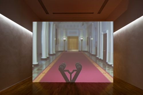 Large projection screen with image of an empty columned hall with red carpet