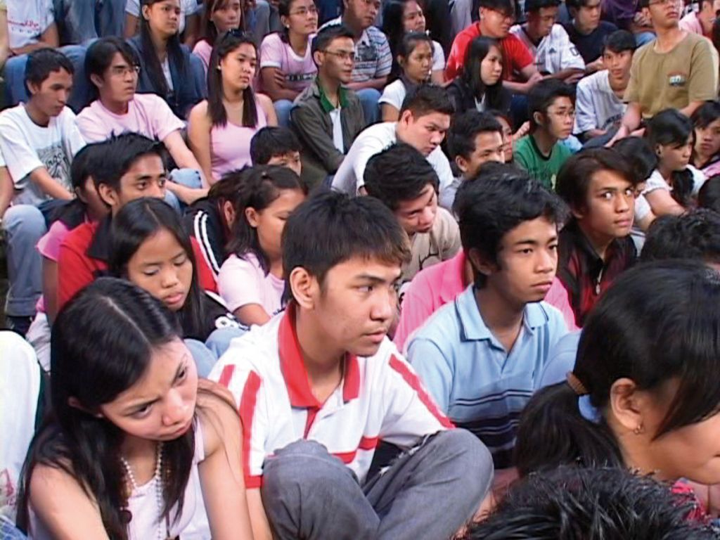 Dense group of seated people, all looking in one direction