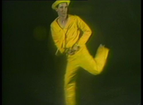 Video-Screenshot: ein Mann in gelbem Matrosenanzug vor dunklem Hintergrund