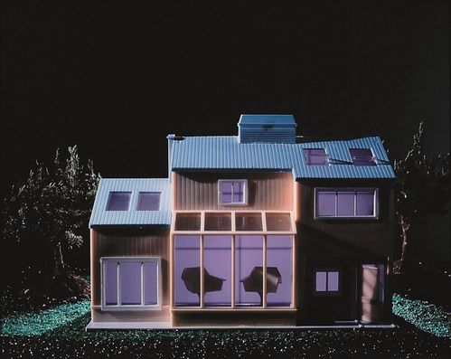 A dollhouse in pale lavender pastel  tones is photographed frontally amid a dark, glistening nighttime landscape.