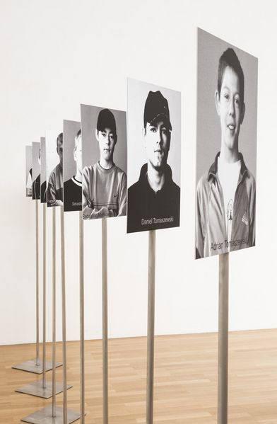  A display stand featuring black-and-white portrait photographs of boys, with names listed at the bottom of each image.