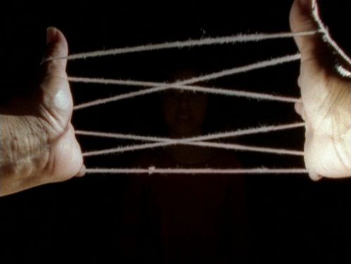 Two hands stretch a thread into a zigzag pattern.