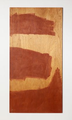 Längliche rechteckicke Holzfläche, an drei Stellen unregelmäßig mit rotbrauner Farbe bemalt.